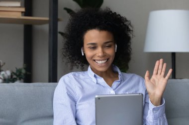Kablosuz kulaklıklı Afro-Amerikan kadın tablet kullanıyor.
