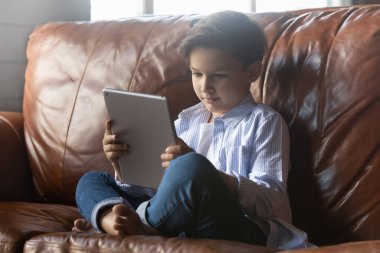 Çocuk kanepede dinleniyor. Elektronik tablet kullanılıyor.