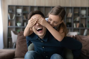 Heyecanlı babaya sürpriz yapan kız, elleriyle gözlerini kapatıyor.