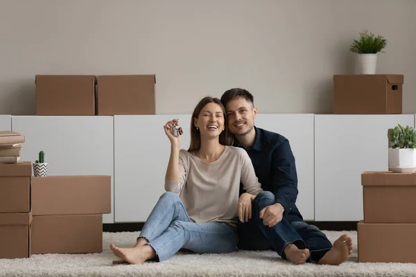 Retrato feliz pareja demostrando llaves, sentado en el suelo, disfrutando de la reubicación — Foto de Stock