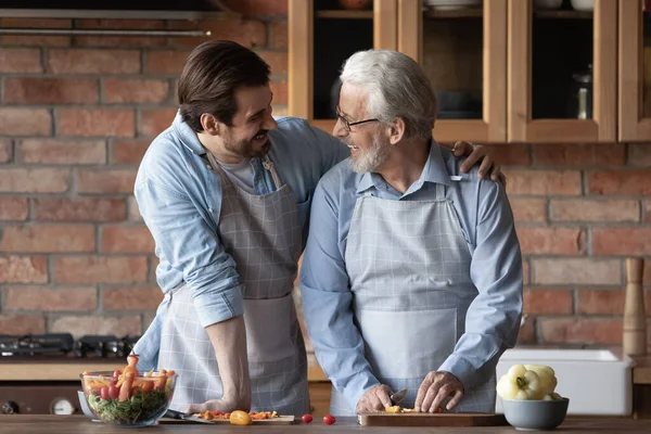 Amour fils millénaire embrasser l'épaule du père retraité profiter de la cuisine ensemble — Photo