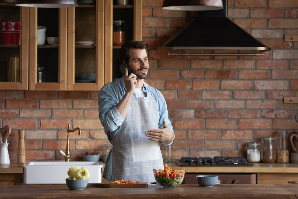 Millennial homme cuisine salade saine parler au téléphone à la cuisine — Photo