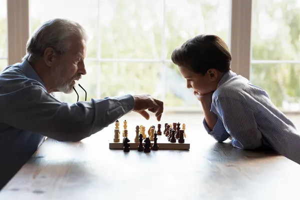Elderly granddad teaching little boy grandkid to play chess game — Stock Photo, Image