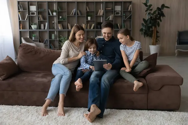 Šťastná rodina s dětmi pomocí tabletu, relaxace na gauči — Stock fotografie