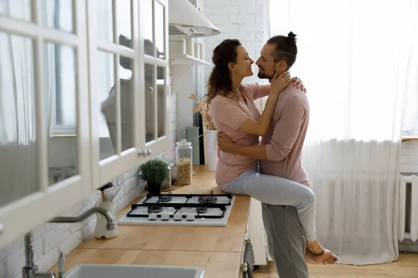 Glückliche junge Frau küsst liebevollen Ehemann zu Hause. — Stockfoto