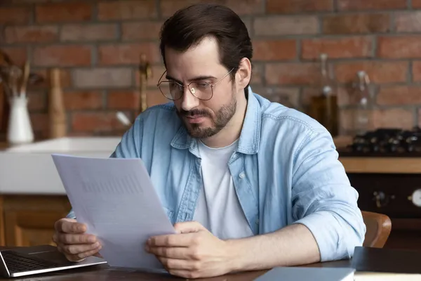 Worried millennial male manage paper documents troubled with statistic reports — Stock Photo, Image