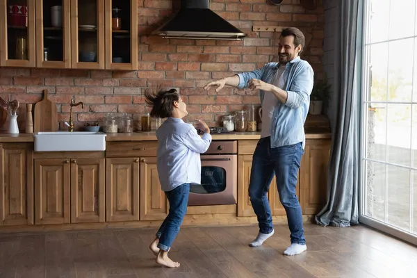 Gelukkige jonge vader kleine zoon dansen op de vloer in de keuken — Stockfoto