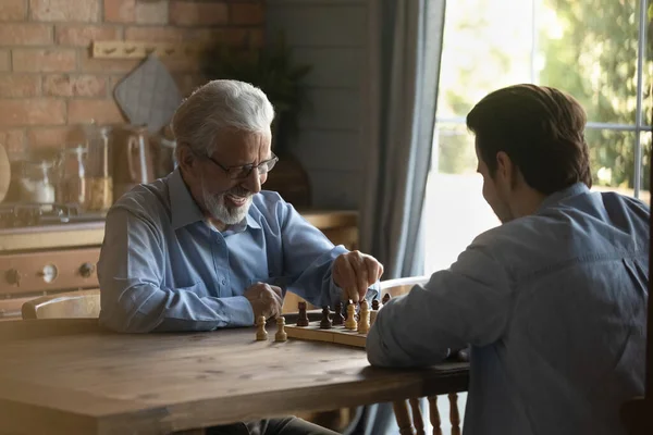 Энтузиаст и старый отец играют в шахматы со взрослым сыном — стоковое фото