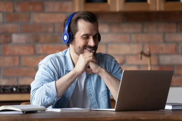 Smiling millennial man in earphones watch webinar on laptop online — Stock Photo, Image