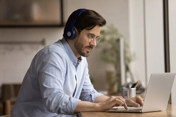 Focused young 30s businessman in headphones using computer. — Stock Photo, Image