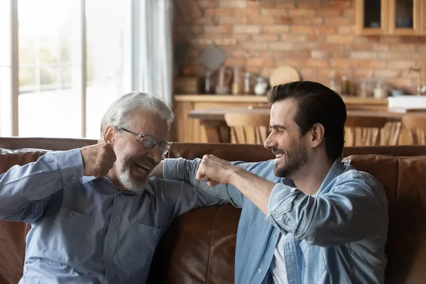 Śmiejący się stary ojciec uderzający pięściami z dorosłym synem — Zdjęcie stockowe