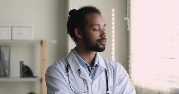 Verträumter junger afrikanischer Arzt ruht sich im Büro aus. — Stockvideo