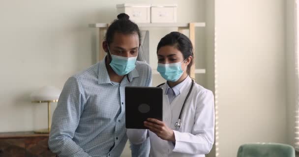 Médico y paciente diverso enfocado usando tableta digital. — Vídeo de stock