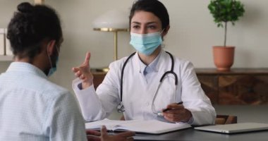 Konsantre olmuş melez doktor ve hasta ofiste konuşuyor..