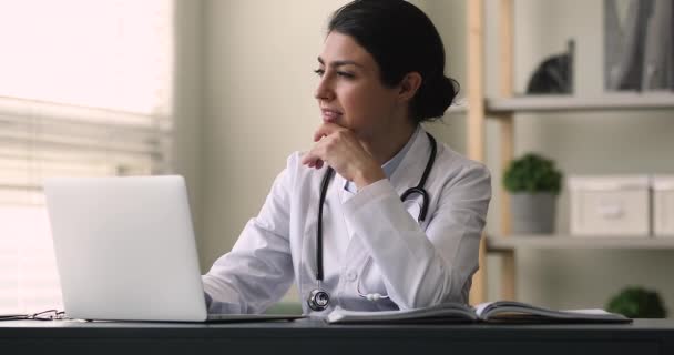 Sorrindo jovem médico indiano trabalhando no computador na clínica. — Vídeo de Stock