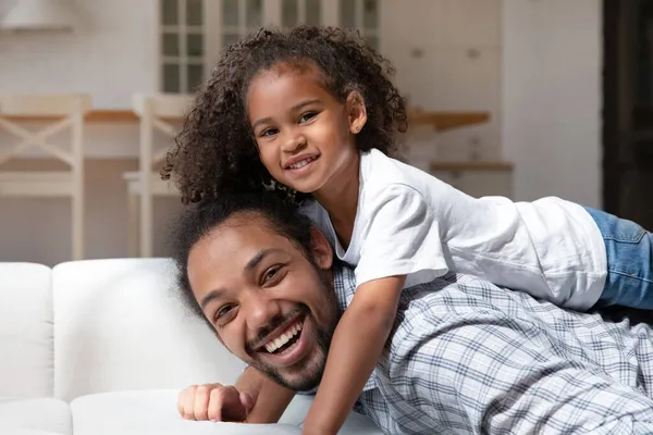 Fille afro-américaine joyeuse reposant sur des papas heureux retour — Photo