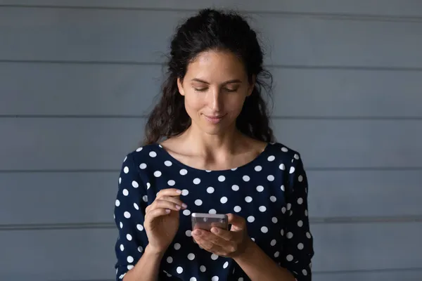 Tevreden duizendjarige Latijnse vrouwelijke mobiele telefoon gebruiker het schrijven van sms-berichten — Stockfoto