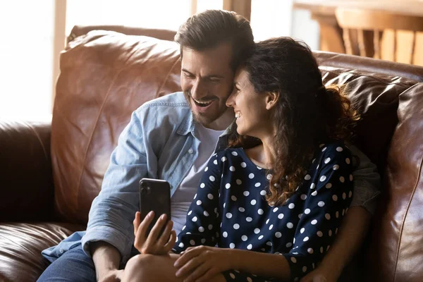 Overjoyed giovane coppia coccole sul divano guardare commedia sul cellulare — Foto Stock