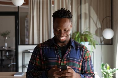 Gülümseyen Afrikalı genç adam cep telefonu uygulamalarını kullanıyor..