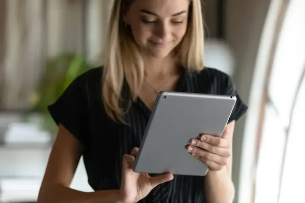 Smiling attractive young businesswoman using touchpad in office. — Stock Photo, Image