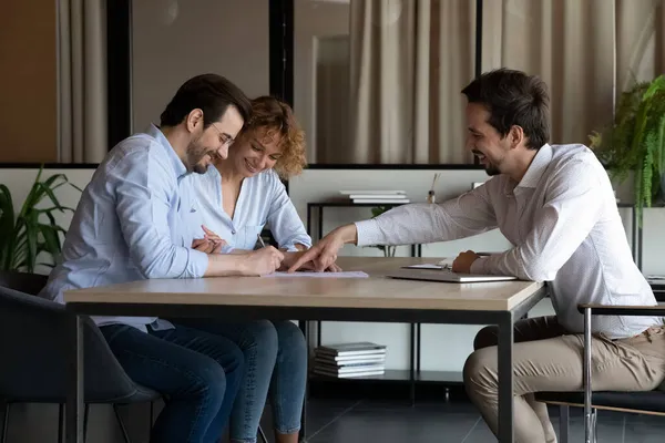 Glimlachende jonge specialist maakt overeenkomst met klanten. — Stockfoto