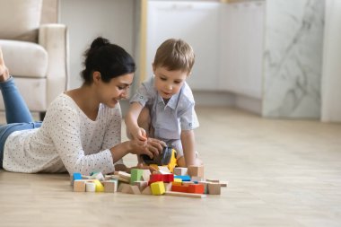 Mutlu bebek bakıcısı ve tatlı anaokulu çocuğu yerde oyun oynuyor.