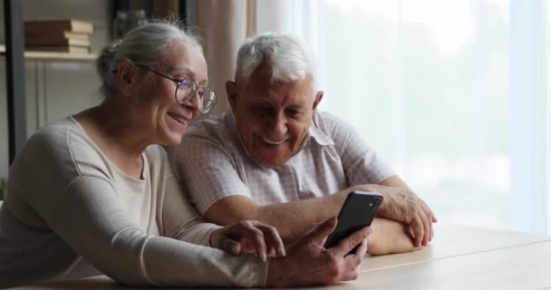 Sorrindo idade mais velha casal assistir vídeo na tela do smartphone — Vídeo de Stock