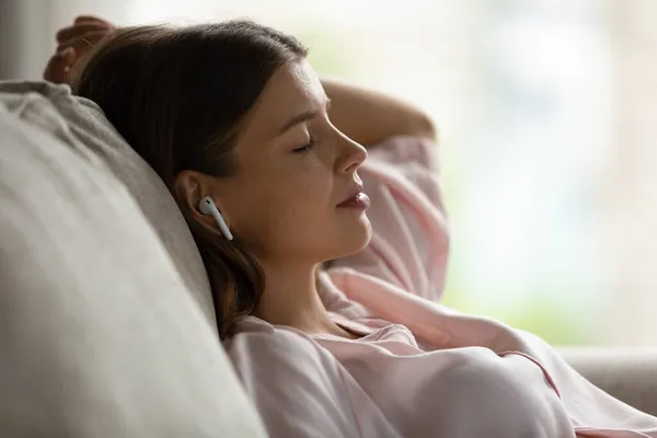 Relaxé jeune femme caucasienne écouter de la musique dans les écouteurs. — Photo