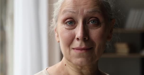 Портрет крупным планом счастливая пенсионерка смотрит в камеру с улыбкой — стоковое видео