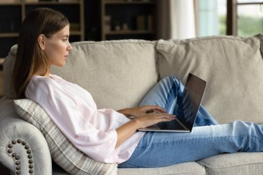 Evde bilgisayar kullanan rahat, mutlu genç bir kadın..