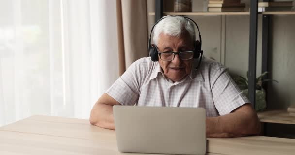 Старший чоловічий одяг навушники конференції онлайн, використовуючи додаток на ноутбуці — стокове відео