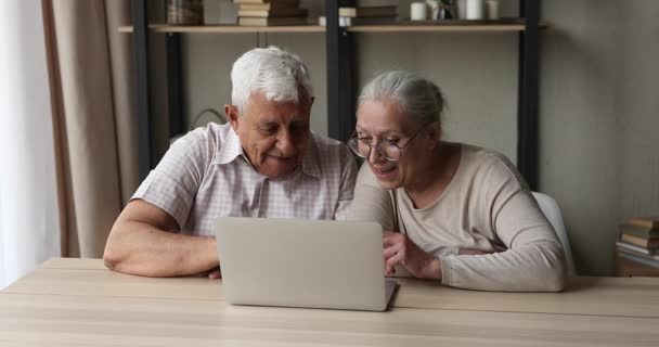 Ενεργό ηλικιωμένοι συνταξιούχοι ζευγάρι απολαμβάνουν τη χρήση φορητού υπολογιστή στο σπίτι — Αρχείο Βίντεο