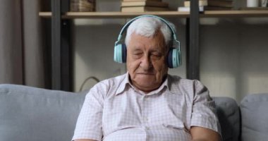 Yaşlı, modern kulaklık takan, müzik dinleyen olgun bir erkek.