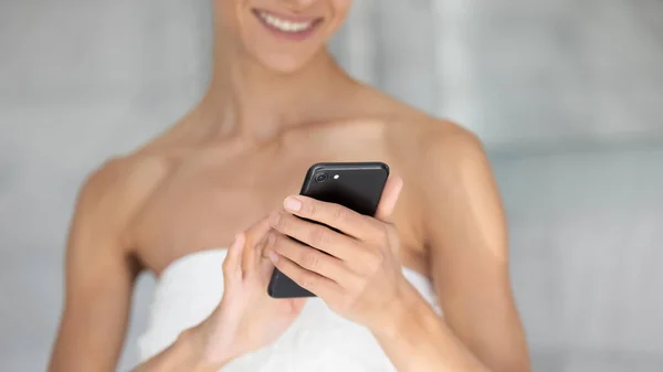 Joven mujer de raza mixta utilizando el teléfono celular después de la ducha. — Foto de Stock