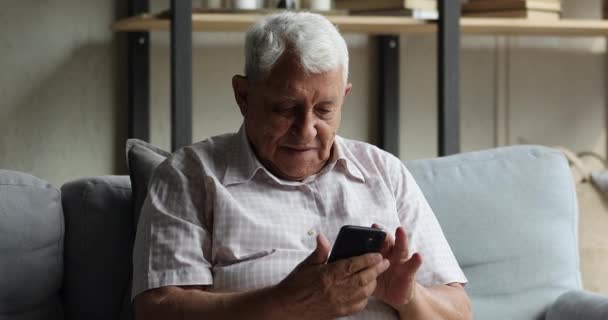Sorrindo homem de meia idade usando o aplicativo móvel no celular moderno — Vídeo de Stock