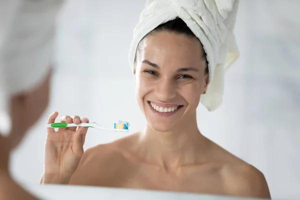 Uśmiechnięta atrakcyjna mieszanka rasy kobieta trzyma szczoteczkę z pastą do zębów. — Zdjęcie stockowe