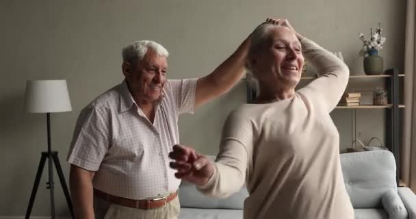 Szeretetteljes középkorú pár nagyszülők tánc keringő a nappaliban — Stock videók