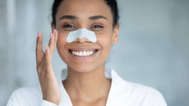 Mutlu güzel Afrikalı etnik kadın burun temizleme bandı kullanıyor..