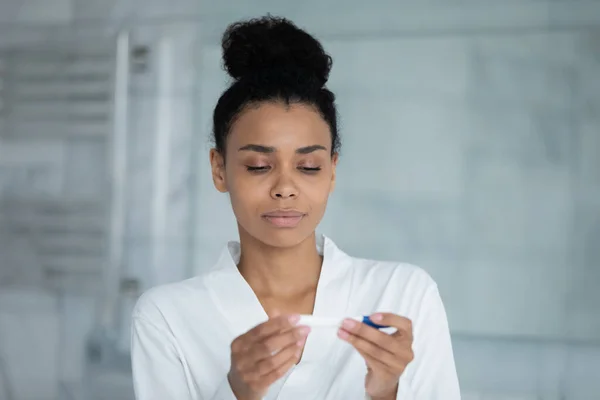 Concentrated young african mixed race woman using pregnancy test. — Stock Photo, Image
