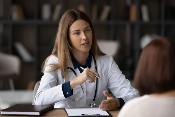 Kvinnlig läkare terapeut i vit uniform konsulterande patient vid möte — Stockfoto