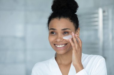 Gülümseyen çekici milenyum Afrikalı kadın krem sürüyor..