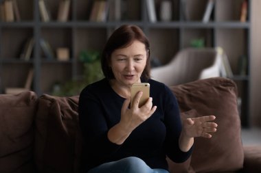 Akıllı telefon kullanan, görüntülü konuşma yapan olgun bir kadın.