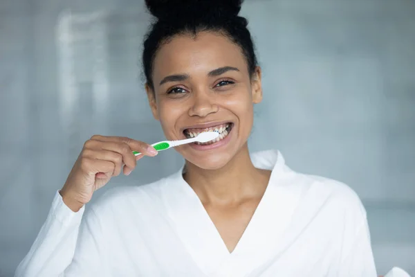 Szczęśliwa młoda Afrykanka myjąca zęby, patrząca w kamerę. — Zdjęcie stockowe