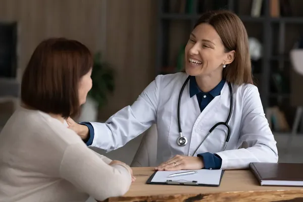 Sonriente mujer terapeuta médico tocando madura mujer paciente hombro, apoyo — Foto de Stock