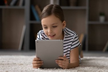 Kafasından vurulmuş, tablet kullanan küçük bir kız, sıcak zeminde yatıyor.