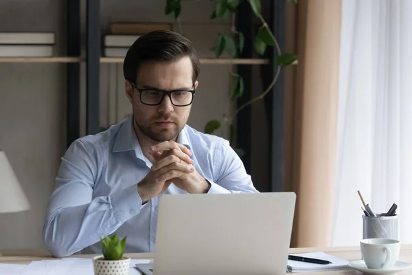Pensativo joven hombre de negocios en gafas de trabajo en la computadora. —  Fotos de Stock