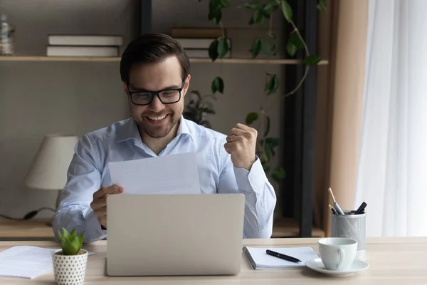 Happy sincere young man reading good news in paper letter. — Stock Photo, Image