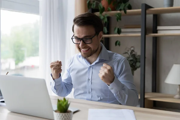 Gelukkige jongeman in bril viert succes op internet. — Stockfoto