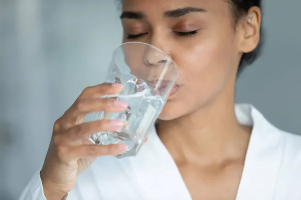 Thirsty young african american woman drinking glass of water. — Stock Photo, Image