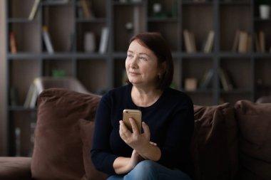 Hayalperest, olgun bir kadın elinde modern bir akıllı telefon tutuyor.